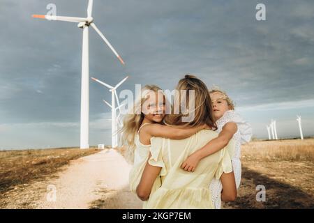 Mère transportant des filles et marchant sur la route devant les éoliennes Banque D'Images