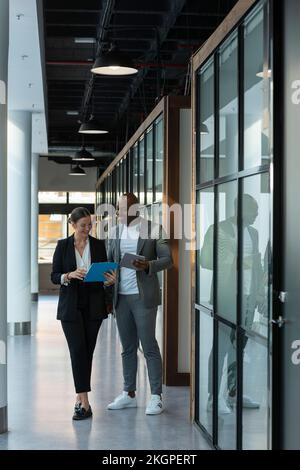 Des collègues souriants discutent dans le couloir au lieu de travail Banque D'Images