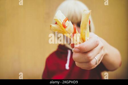 Femme montrant des frites avec du ketchup devant le visage Banque D'Images