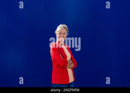 Femme souriante aux bras croisés portant un blazer rouge Banque D'Images