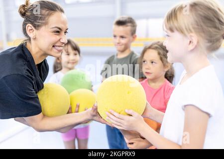 Joyeux professeur donnant du ballon à l'étudiant au terrain de sport de l'école Banque D'Images