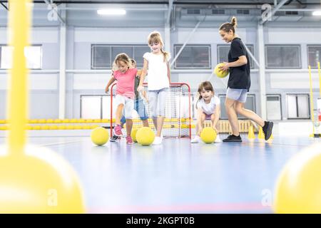 Élèves et enseignant jouant avec des balles au terrain de sport de l'école Banque D'Images