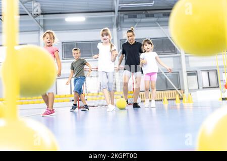 L'enseignement des enseignants donne des coups de pied aux élèves avec du ballon sur le terrain de sport de l'école Banque D'Images