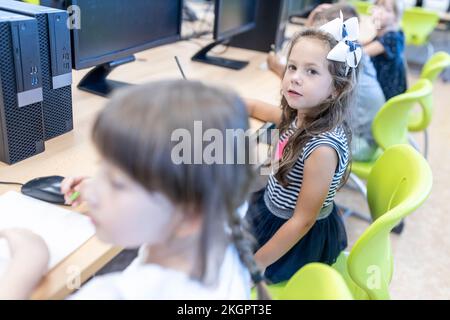 Fille assise à un bureau avec des amis en classe à l'école Banque D'Images