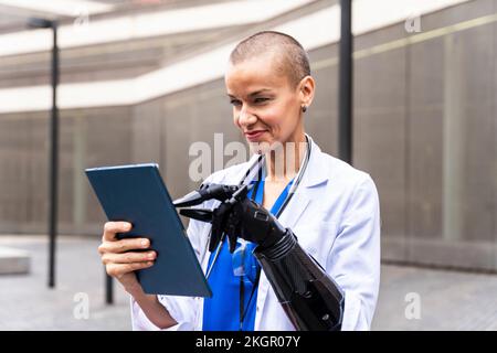 Femme souriante médecin utilisant un Tablet PC avec une main artificielle Banque D'Images