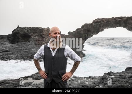 Homme mature avec les mains sur la hanche debout devant la mer Banque D'Images