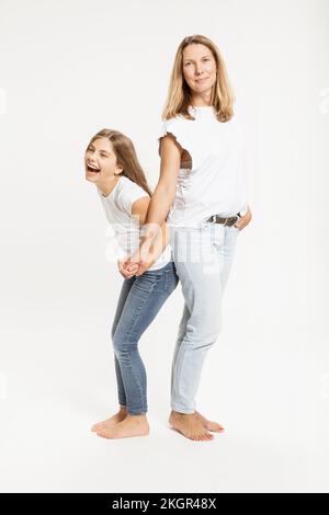 Fille riant et tenant la main de mère en studio Banque D'Images