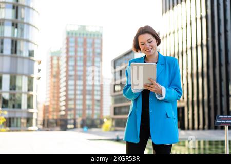Femme d'affaires souriante portant un blazer bleu sur une tablette PC Banque D'Images