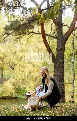 Une femme blonde qui a fait un chien mignon dans la forêt d'automne Banque D'Images