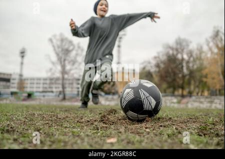 Garçon jouant au football sur le terrain Banque D'Images