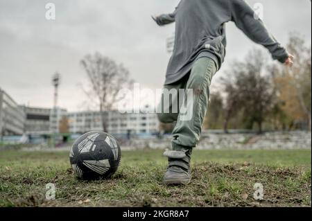Un garçon donne un coup de pied au ballon de football sur le terrain de sport Banque D'Images