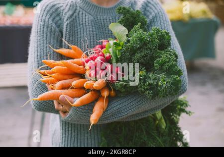 Mains de femme tenant des légumes frais au marché Banque D'Images