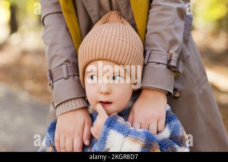 Mignon garçon portant un chapeau en tricot debout avec la mère dans le parc Banque D'Images