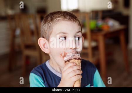 Un garçon mange de la crème glacée à la maison Banque D'Images
