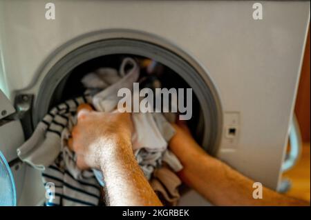 Mains de l'homme qui retire les vêtements de la machine à laver Banque D'Images