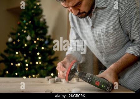 Un artisan qui fait des ébauches en bois à travers une meuleuse à la maison Banque D'Images