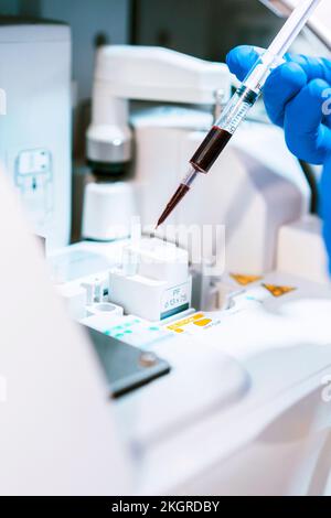 Main du médecin analysant un échantillon de sang en laboratoire Banque D'Images