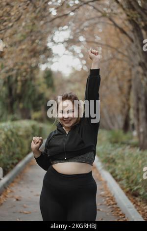 Bonne femme gestante poing avec la main levée sur la piste de marche dans le parc Banque D'Images