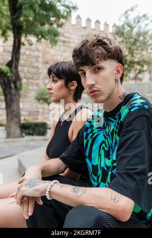 Jeune homme avec tatouage assis par petite amie sur l'escalier Banque D'Images