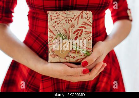 Femme en robe rouge tenant un cadeau de Noël Banque D'Images