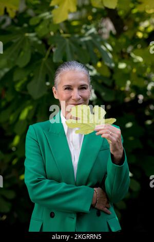 Femme aînée souriante portant un manteau vert tenant une feuille de figue Banque D'Images