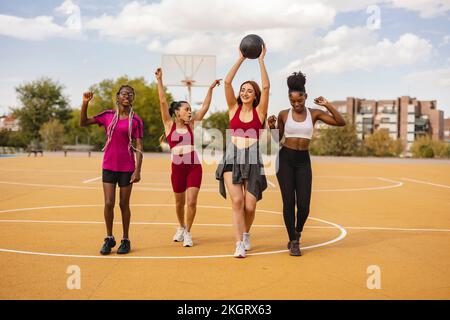 Bonne jeune femme marchant avec le basket-ball sur le terrain de sport Banque D'Images