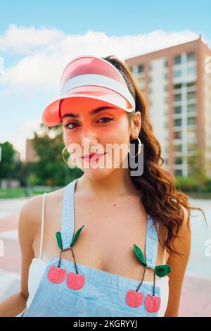 Belle femme souriante portant un pare-soleil debout sur un terrain de sport Banque D'Images