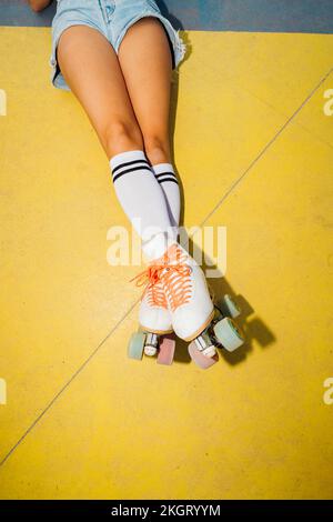 Jambes de femme portant des patins à roulettes couchés sur un terrain de sport Banque D'Images