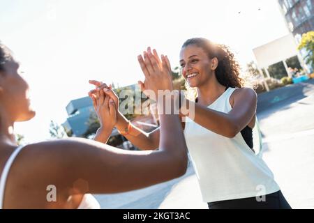 Des amis heureux qui donnent des cinq hauts par beau temps Banque D'Images