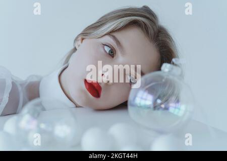 Adolescente avec rouge à lèvres regardant le ballon de Noël sur la table Banque D'Images