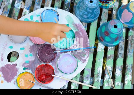 Main de la petite fille peinture pots de fleurs Banque D'Images