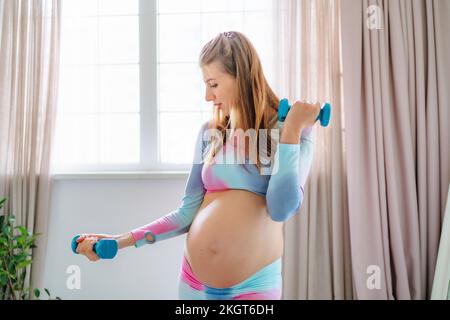 Femme enceinte l'entraînement avec haltères à la maison Banque D'Images