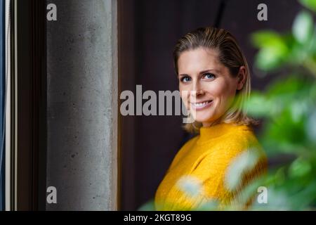 Bonne femme d'affaires portant un chandail jaune au bureau Banque D'Images