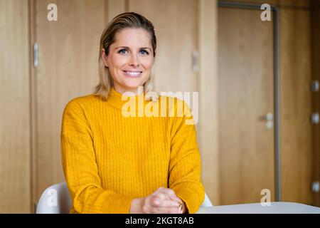 Smiling businesswoman sitting in office Banque D'Images