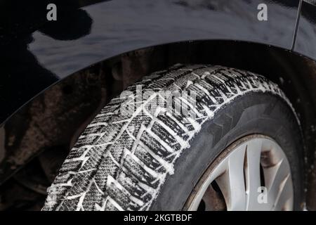 Gros plan sur une roue de voiture avec pneus d'hiver peu usés pendant le tournage pour une conduite sûre dans la neige et la glace. Banque D'Images