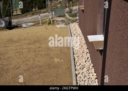 Un chemin de drainage fait de pierres décoratives autour du mur de la maison Banque D'Images