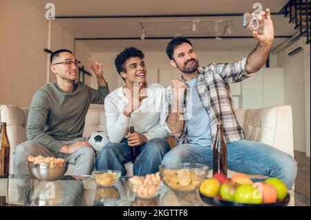 Compagnie de joyeux amis multiethniques prenant des selfies à l'intérieur Banque D'Images