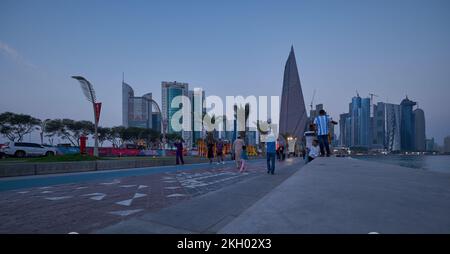 Photo de la corniche de Doha au coucher du soleil montrant la préparation du Qatar pour la coupe du monde de la FIFA Qatar 2022 avec les habitants et les visiteurs marchant sur la promenade Banque D'Images