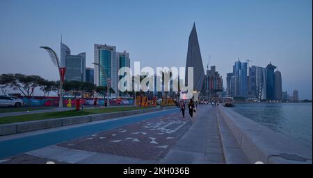 Photo de la corniche de Doha au coucher du soleil montrant la préparation du Qatar pour la coupe du monde de la FIFA Qatar 2022 avec les habitants et les visiteurs marchant sur la promenade Banque D'Images