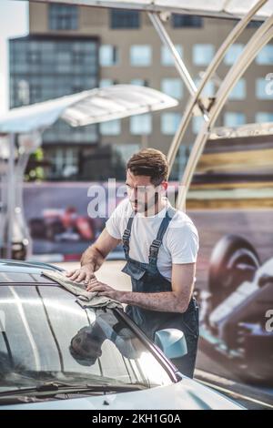 Un employé de station-service spécialisé polissage manuel du véhicule du client Banque D'Images