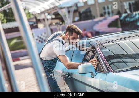 Un professionnel de la voiture de finition lustrant un véhicule de client à la main Banque D'Images