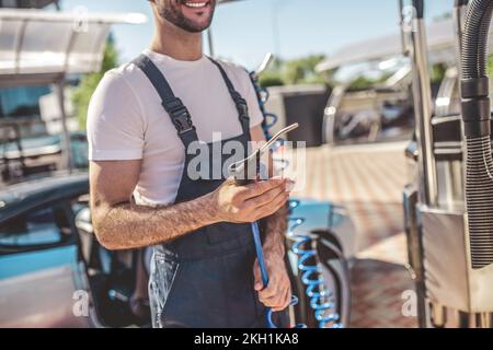 Un employé de station-service joyeux se préparant à une procédure de lavage de voiture client Banque D'Images