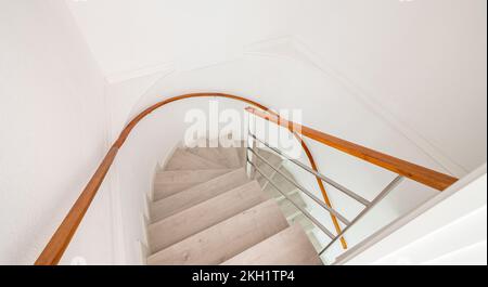 Escalier en spirale avec escaliers blancs et garde-corps en bois sur le mur à l'intérieur d'une maison. Banque D'Images