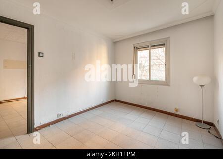 Chambre vide et spacieuse avec fenêtre et murs sales dans un ancien appartement avant rénovation. Banque D'Images