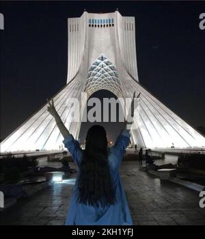 Téhéran, Iran. 17th novembre 2022. Une fille se tient devant la Tour Azadi à Téhéran sans le foulard légalement requis et montre le signe de la victoire avec les deux mains. La violence dans les rues a fait rage en Iran du jour au lendemain, alors que les manifestations déclenchées par la mort d'Amini à 16 septembre se sont intensifiées à l'anniversaire de la répression meurtrière de 2019. Amini, une iranienne de 22 ans d'origine kurde, est décédée sous la garde de la célèbre police de moralité après son arrestation pour une violation présumée du code vestimentaire strict de l'Iran pour les femmes. (Credit image: © Anonyme via ZUMA Press Wire) Banque D'Images