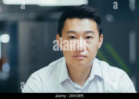 Gros plan. Portrait d'un homme d'affaires asiatique au bureau. Il regarde sérieusement l'appareil photo. Banque D'Images