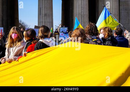 Les gens portent un grand drapeau ukrainien lors d'une manifestation contre la guerre russe en Ukraine. Banque D'Images