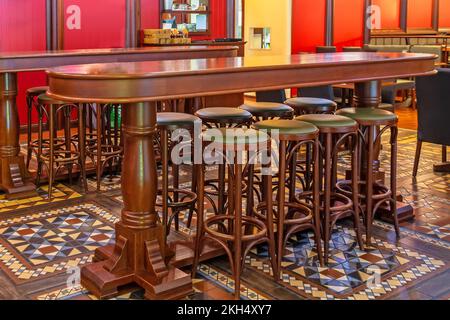 Rangée de chaises hautes en bois dans un bar devant une table dans un pub Banque D'Images