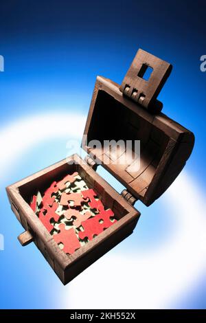 Coffre en bois avec pièces de puzzle Jigsaw sur fond bleu Banque D'Images
