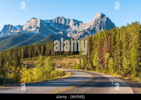 Une route sinueuse à travers les bois dans les Rocheuses canadiennes lors d'une journée d'automne ensoleillée près de Canmore, Alberta, Canada Banque D'Images